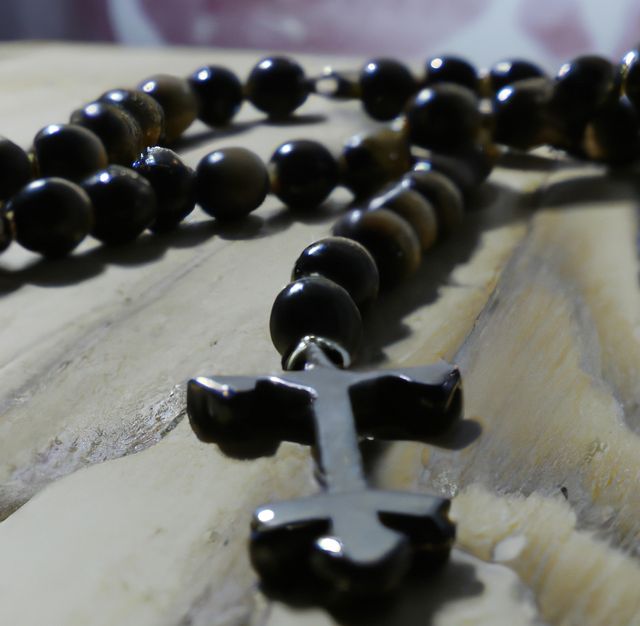 Close up of black rosary with cross on wooden background. Religion, faith and prayer concept.