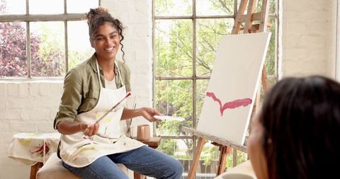Art Instructor Teaching Painting Techniques to Student in Bright Studio