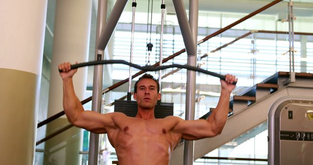 Muscular man working his arms on the weight machine at the gym - Download Free Stock Photos Pikwizard.com