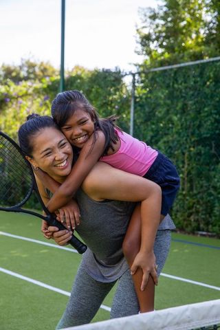 Playful Mother-Daughter Bonding on Tennis Court with Racket