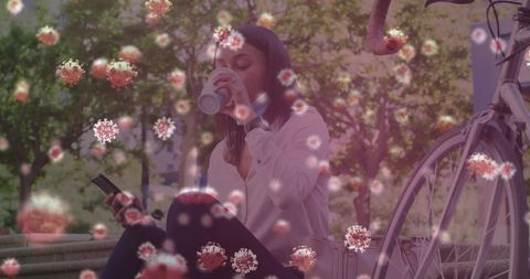 Woman drinking coffee with floating virus symbols outdoors