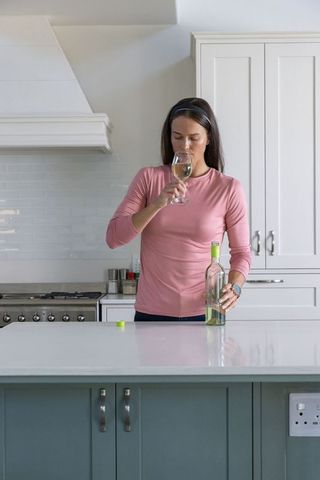 Young woman in kitchen tasting white wine