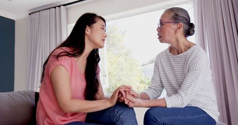 Mother and Daughter Holding Hands Talking in Living Room