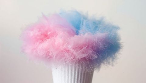 Pastel pink and blue cotton candy tufts on white ridged cup, soft confection still life