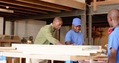 Craftsmen Collaborating on Woodworking Project in Industrial Workshop