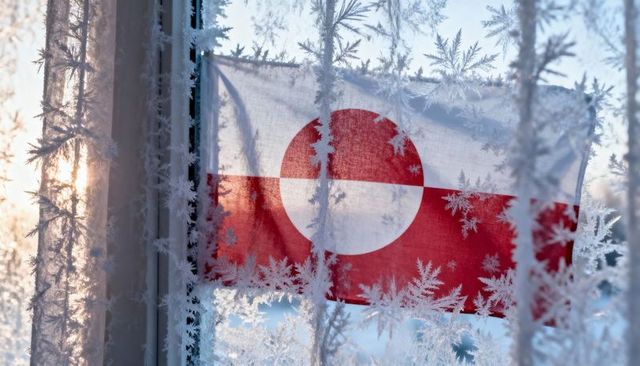 Frost-kissed greenland flag backlit by arctic sunrise through frosted home window