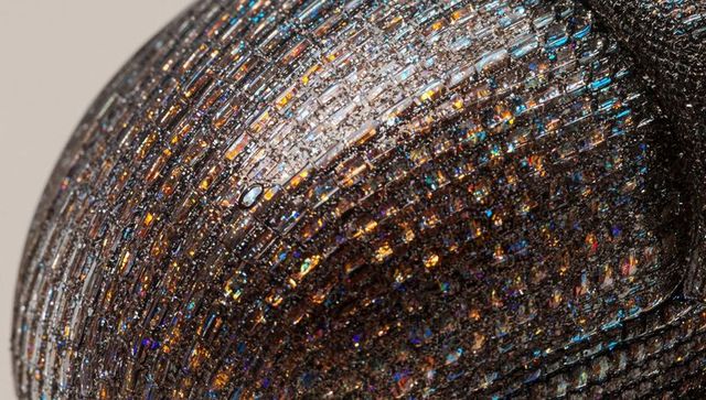 Macro iridescent sequin dome shimmering with glossy droplet and metallic tile texture