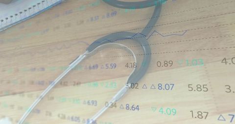 Stethoscope Resting on Wooden Desk with Financial Data Overlay for Healthcare Analytics