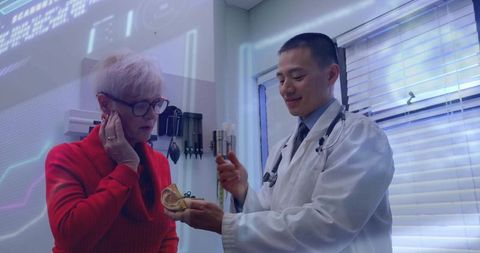 Doctor explaining ear anatomy to senior female patient in modern clinic