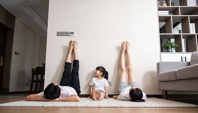 Family practicing legs-up relaxation pose against wall in cozy living room for bonding