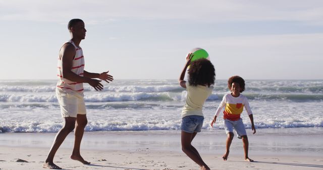 African american father and his children playing with a ball on the beach. healthy outdoor leisure time by the sea.