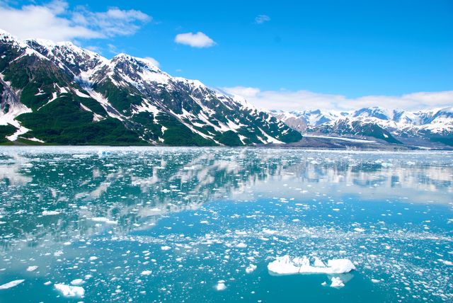 Panoramic view of a pristine Alaskan glacier with snow-capped mountains reflecting in icy waters. Perfect for nature, travel, and adventure themes, showcasing the untouched beauty and serene landscape of Alaska.