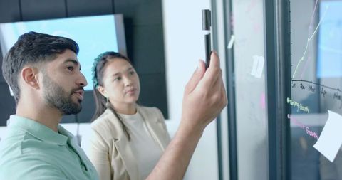 Coworkers Analyzing Data on Glass Board in Modern Office