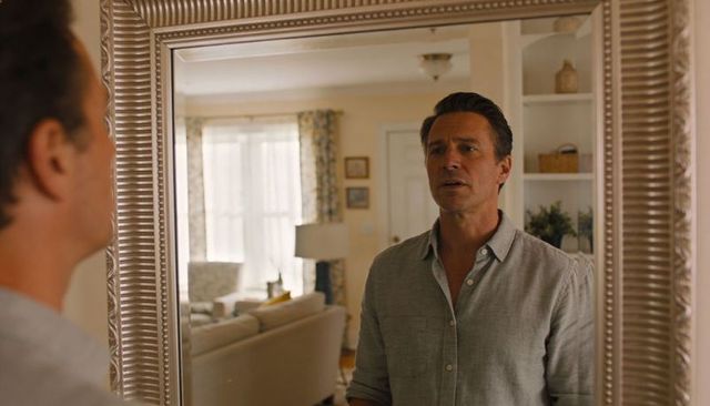 Man studying reflection in ornate mirror in cozy living room showing quiet contemplation