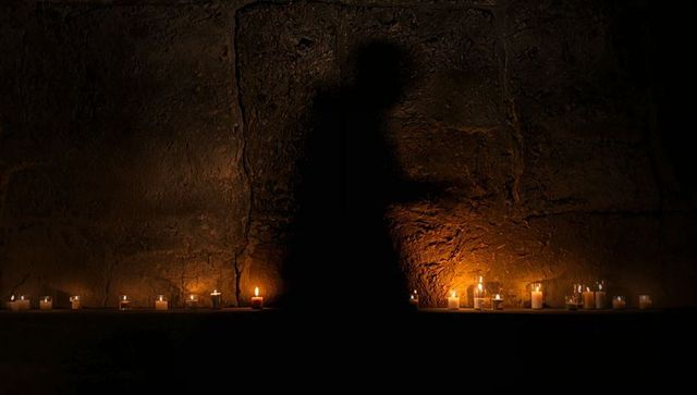 Silhouette Over Candlelit Stone Chamber Evoking Mystery