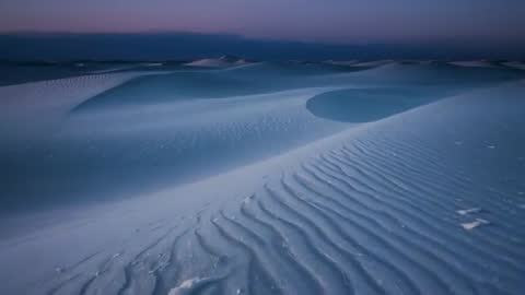 Surveying dune field at dusk revealing rippled sand textures and purple-blue twilight
