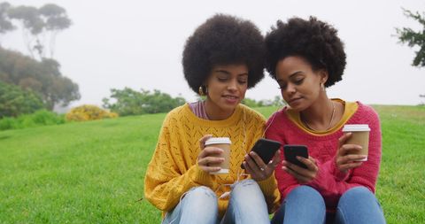 Sisters Relaxing with Coffee and Phones in Sunny Park - Download Free Stock Images Pikwizard.com