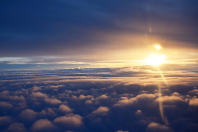Beautiful sunrise seen from an airplane window, with the sun rising above thick clouds, casting a golden light. Ideal for use in travel blogs, advertisements, inspirational graphics, and desktop backgrounds.