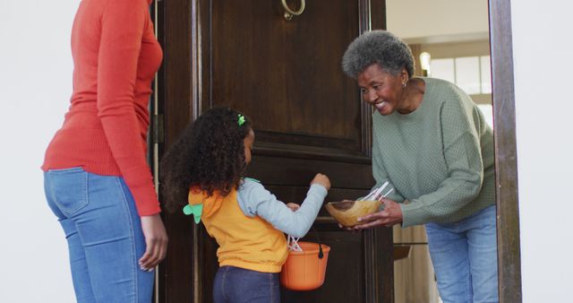 Senior woman greeting a young girl with Halloween treats at front door, reflecting holiday spirit and family tradition. Ideally used for content focusing on Halloween celebrations, family activities, and festive traditions.