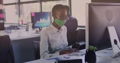 Businesswoman with Face Mask Analyzing Financial Data on Computer