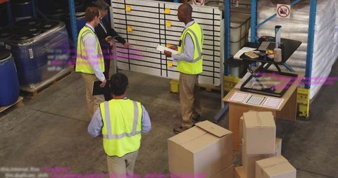 Warehouse team conducting safety briefing and planning at staging area with whiteboard and boxes