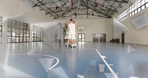 Five players huddling on indoor basketball court during training session