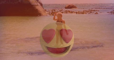 Child in floral bikini on rocky beach overlaid with heart-eyes emoji