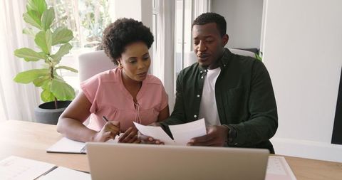 Friends Collaborating on Project at Home Using Laptop