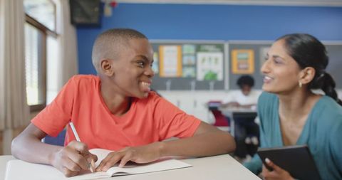 Educator Assisting Student Writing in Classroom Setting