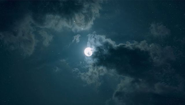 Radiant Full Moon Amidst Ethereal Night Clouds
