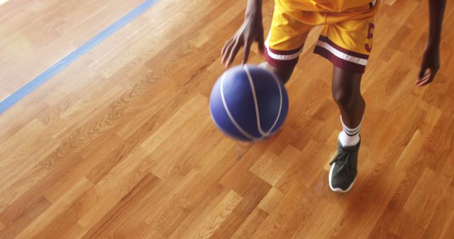 Basketball player practicing dribbling drill in the court indoors
