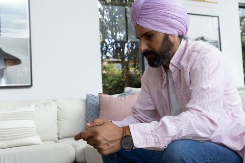 Indian man engaged with smartphone in bright living room