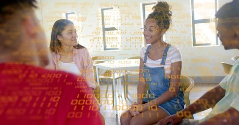 Students collaborating on coding project with binary code overlay in modern classroom