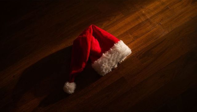 Resting Red Santa Hat on Dark Hardwood under Warm Spotlight, Cozy Christmas Mood, Solitary