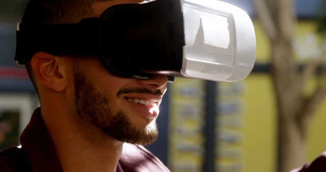 Close-up of smiling man enjoying virtual reality experience. Perfect for use in technology, gaming, and interactive content contexts. Highlights modern immersive experiences and can be used in promotional or educational materials.
