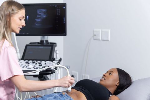 Clinician performing prenatal ultrasound on african american pregnant woman in clinic
