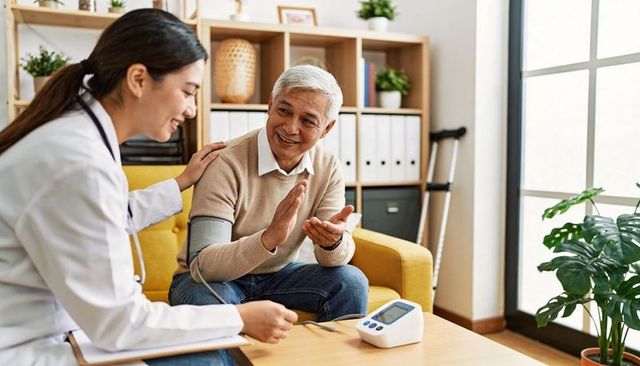 Home health visit: nurse measuring senior blood pressure while sharing conversation