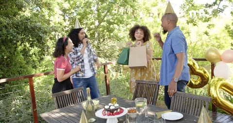 Diverse Friends Celebrating Birthday on Sunny Terrace with Party Hats and Gifts