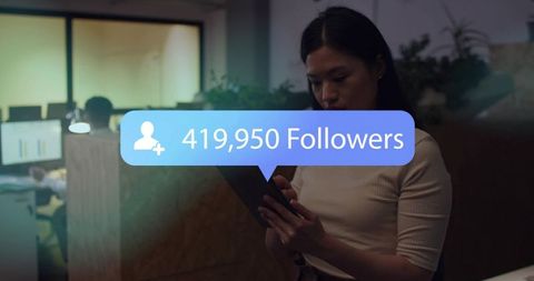 Woman checking smartphone in dim office with 419,950 followers notification bubble
