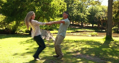 Playful middle-aged couple enjoying outdoor park day