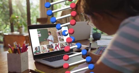 Child studying genetics online at home leaning over laptop with dna strand overlay and notebook