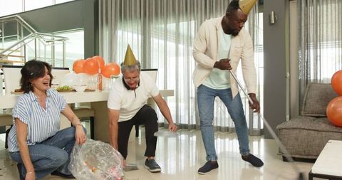 Diverse colleagues cleaning up after festive office celebration