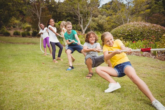Children engaging in a fun tug of war game in a park. Ideal for illustrating teamwork, outdoor activities, childhood fun, and group play. Perfect for use in educational materials, advertisements for outdoor events, and articles on children's health and fitness.