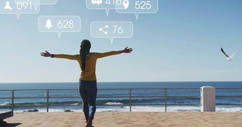 Woman stretching arms facing ocean on promenade with social media icons overlay, seaside freedom