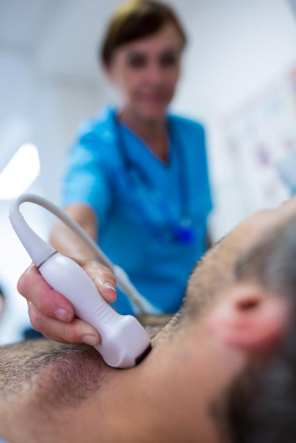 Medical professional performing thyroid ultrasound on male patient in hospital. Useful for healthcare, medical diagnostics, patient care, and hospital-related content.