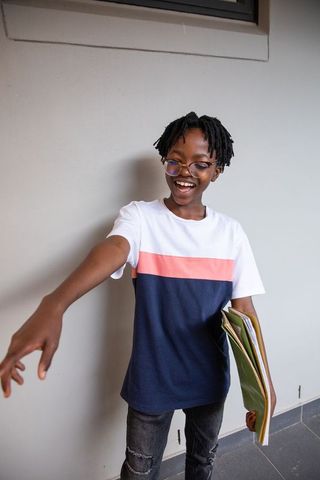 Teen Student Smiling with Notebooks and Casual Style in School Hallway