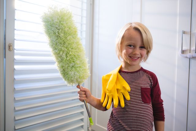 Portrait of boy holding a mop at home