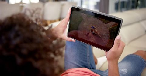 Young man watching baseball replay on tablet at home