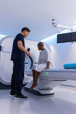 Asian radiology technician assisting african american patient preparing for ct scan