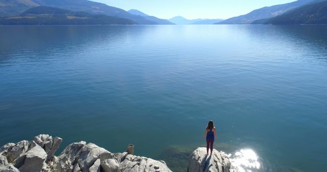 Solitary Woman on Rocky Shore of Majestic Lake - Download Free Stock Images Pikwizard.com